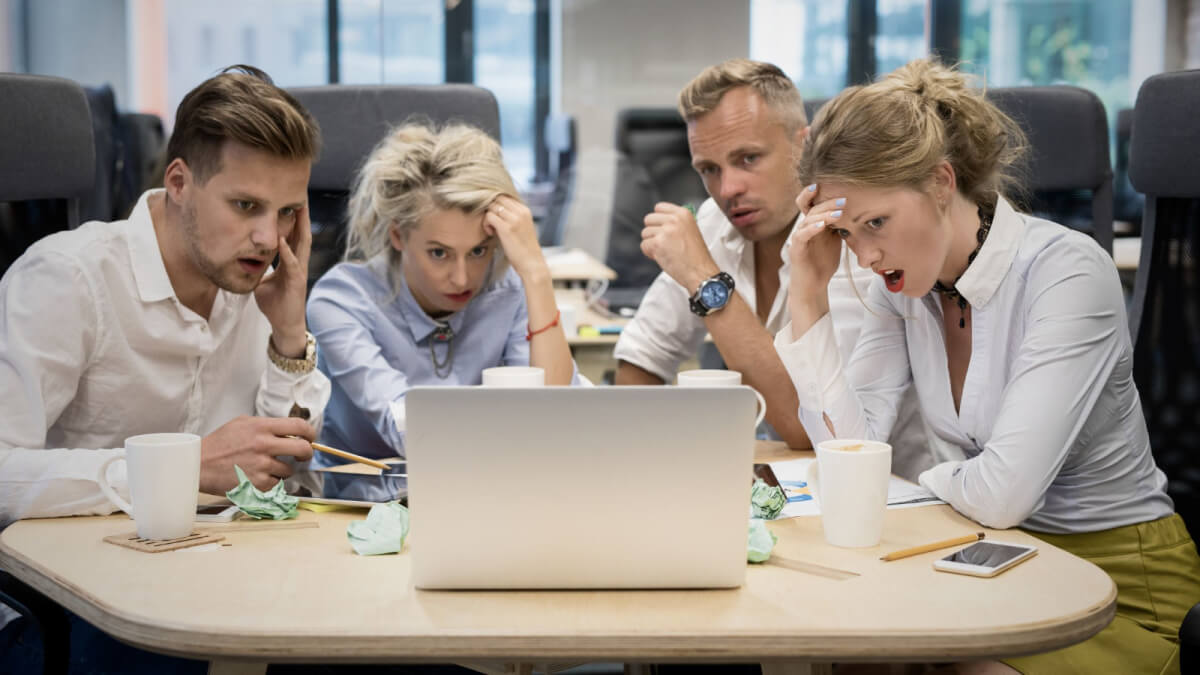 Group of people sitting at a table looking at a laptop